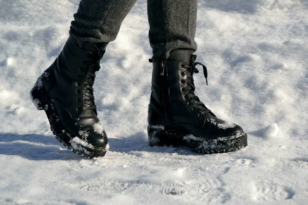 Woman\'s legs in high black boots walking down the street in the snow