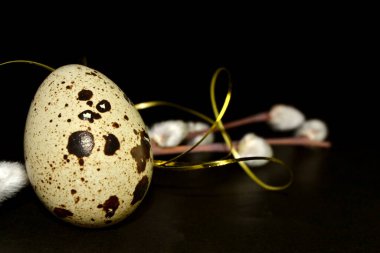 Paskalya bıldırcın yumurtası ve arka planda altın kurdeleli söğüt dalları