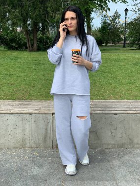 Parkta cep telefonuyla konuşan bir kadın.