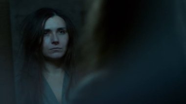 Genç bir kadın aynadaki yansımasına şaşkınlık ve hayal kırıklığıyla bakıyor. Gergin bir duygusal an kendinden şüphe etme, iç mücadele ve kırılganlık gösteriyor.. 