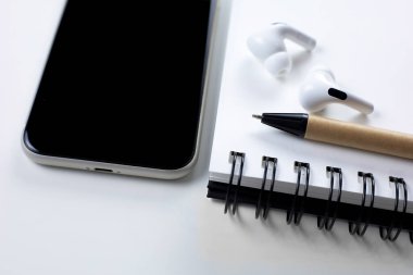 cep telefonu kulaklığı, kalem ve defter izole halde yatıyordu.