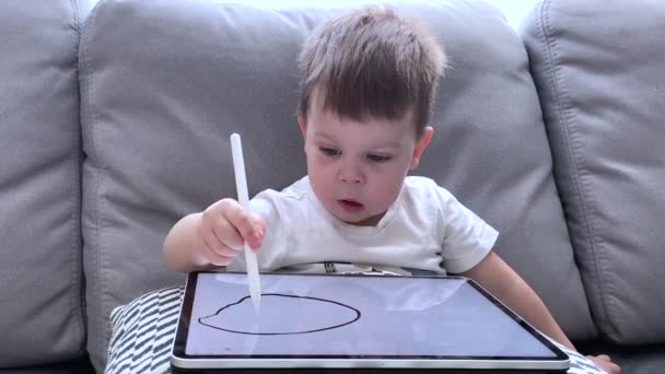 Little boy child drawing funny face on tablet with pencil pen, emotions of a kid close-up — Stock Video