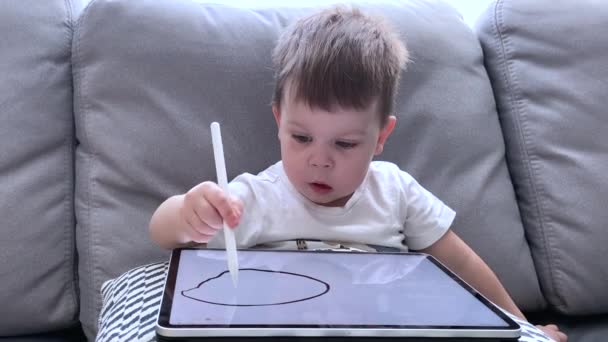 Niño pequeño dibujando cara divertida en la tableta con lápiz pluma, emociones de un niño primer plano — Vídeos de Stock