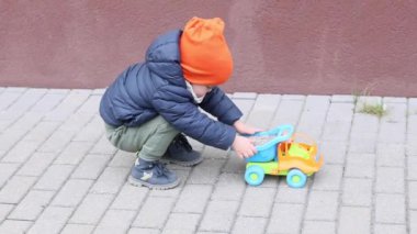 Küçük çocuk bahar gününün dışında oyuncak pistiyle oynuyor. Çok renkli. 