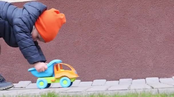 Malý chlapec kluk hraje s autíčkem mimo pomalý nízký úhel pohledu — Stock video