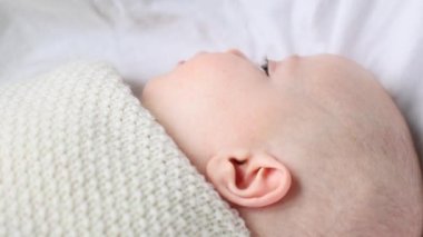 Beyaz battaniyeye sarılmış bebek esniyor