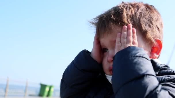 Portrait de garçon pleurant enfant debout seul à l'extérieur tenant la chaleur avec deux mains — Video