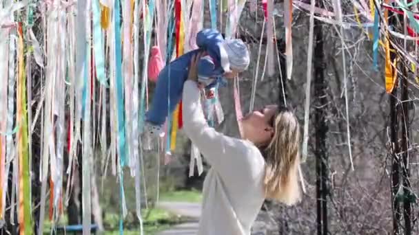 Matka drží své dítě nad hlavou ve vzduchu v barevných stuhách — Stock video