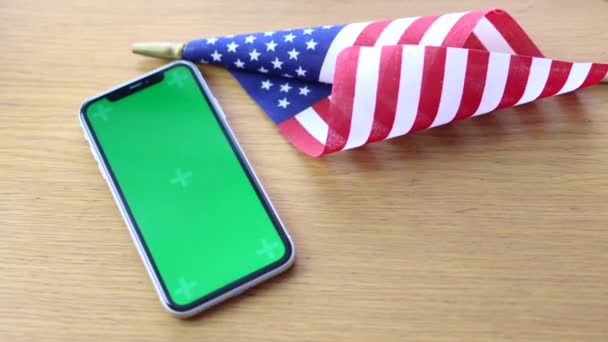 Αμερικανική σημαία που βρίσκεται στο τραπέζι με το κινητό τηλέφωνο chroma κλειδί mockup οθόνη — Αρχείο Βίντεο