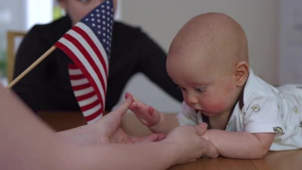 Baby lying on the belly and looking at American usa flag — Stok video