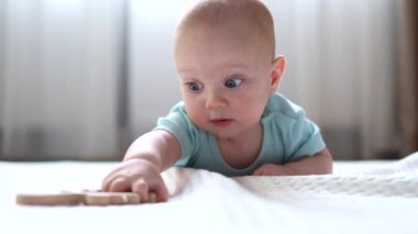 infant baby lying on the stomach playing with wooden toy