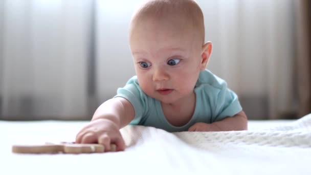 Infant baby lying on the stomach playing with wooden toy — Stok video