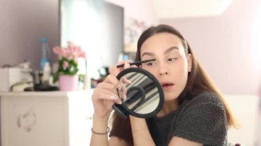 Genç bayan makyaj yapıyor. Göz kapağına gölgeler sürüyor.