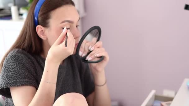 Jovem mulher sentada na cadeira e fazendo-se maquiagem olho — Vídeo de Stock