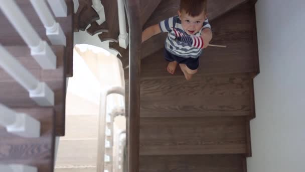 Szczęśliwy chłopiec macha nam flagą schodząc na dół w domu — Wideo stockowe
