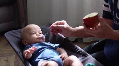 Anne elmayı çay kaşığıyla temizler ve bebeği besler, ek bebek maması konsepti