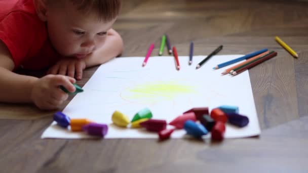一个3岁的小男孩躺在地板上，用绿色铅笔画画的肖像 — 图库视频影像