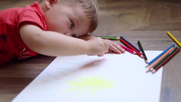 小男孩躺在地板上，用彩色铅笔画出夏天的图画 — 图库视频影像