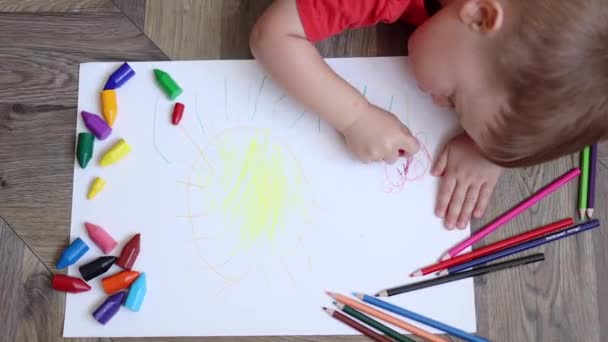 Vista dall'alto di un ragazzo che disegna fiori e sole sul pavimento concetto di educazione precoce — Video Stock