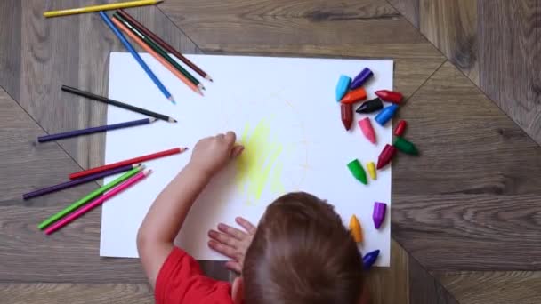 Мальчик рисует желтое солнце мелками — стоковое видео