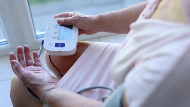 Mature senior woman measures blood pressure with close-up monitor — Stok video