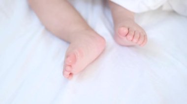 Beyaz battaniyede hareket eden minik bebek bacakları.