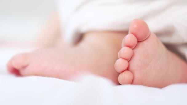 Beyaz battaniyede hareket eden minik bebek bacakları. — Stok video