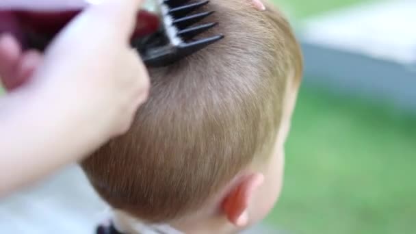 Vista de cerca de corte de pelo niño con un proceso de corte de pelo por peluquero — Vídeo de stock