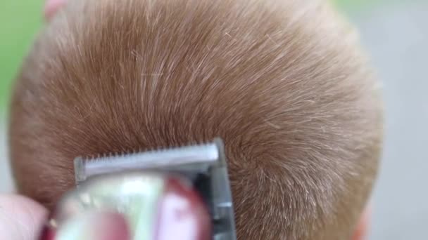 Närbild av frisyr klippare klippa hår på en topp av en childs huvud, processen för frisyr av frisör — Stockvideo