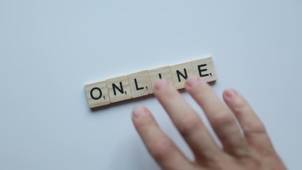 Hand bewegende woord online samengesteld uit afzonderlijke houten letters op witte achtergrond. online business onderwijs cursussen internet concept — Stockvideo