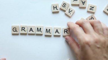 hand composing word grammar from wooden letters on white background