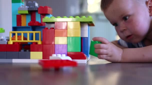 Крупним планом портрет маленького хлопчика, який грає з іграшковими блоками цегли — стокове відео