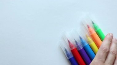 El, beyaz arka planda hareket eden çok renkli işaretler koyuyor. Okula dönüş çizim malzemesi konsepti 
