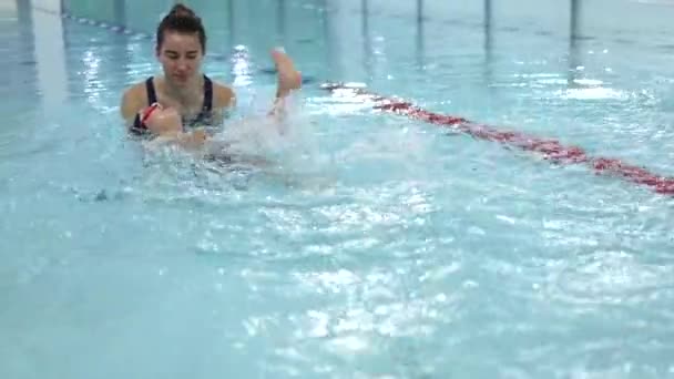 Classe di nuoto allenatore insegna ragazzino a nuotare sulla schiena schizzi gambe in piscina — Video Stock