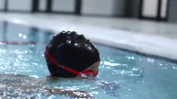 Menino pequeno em água preta boné mergulha na piscina na aula de natação — Vídeo de Stock