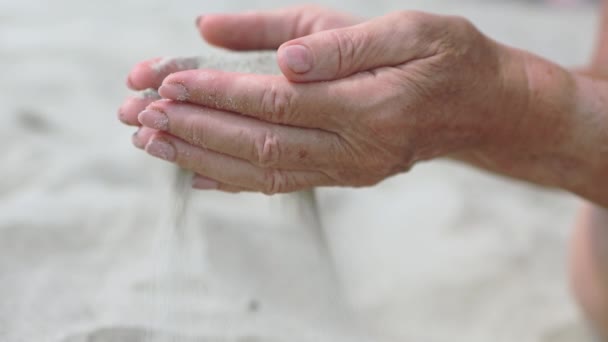 Seniorenhanden die zand door vingers gieten. tijdreizen — Stockvideo