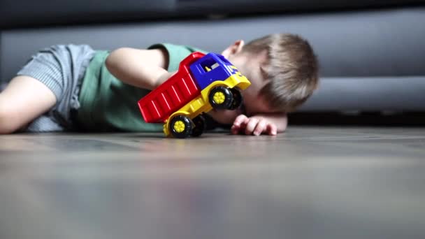 Mały chłopiec dziecko leżące na podłodze w domu w domu bawiąc się samochód zabawka — Wideo stockowe