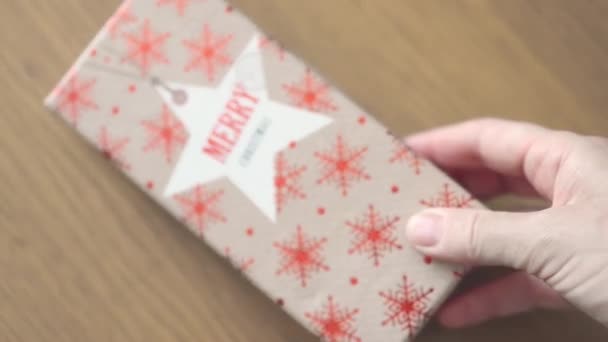 Żeński strony wprowadzenie czerwony brązowy rzemiosło prezent pudełko ze słowami Wesołych Świąt na stole — Wideo stockowe