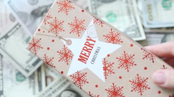 Mano poner caja de regalo de Navidad en dólares estadounidenses fondo de dinero — Vídeo de stock