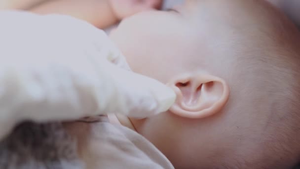 Lékaři ruku v bílé rukavici zkoumá šeky miminko ucho — Stock video