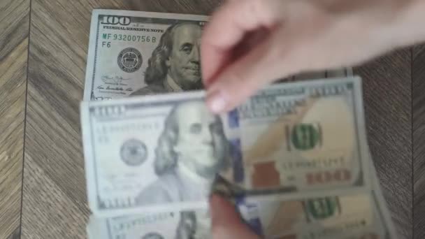 Ženské ruce recounting stack amerických dolarových bankovek na dřevěném pozadí — Stock video