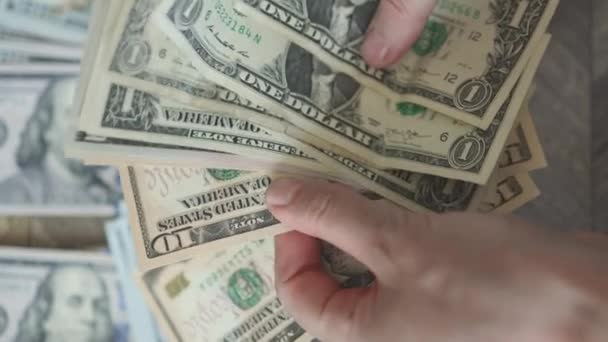 Persoon die kleine biljetten telt Amerikaanse dollar bankbiljetten met honderd dollar biljetten op een achtergrond — Stockvideo