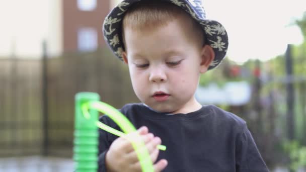 Funny caucasian child kid boy in black shirt and hat playing outside with string — Stock Video