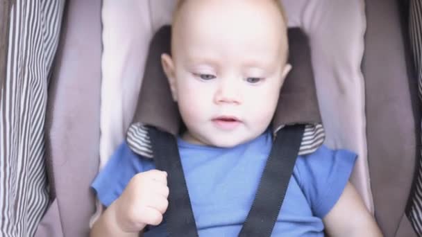 Olhos azuis felizes bebê infantil brincando com as pernas no carrinho marrom ao ar livre em quente — Vídeo de Stock