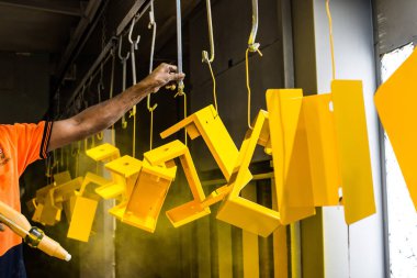 Metal parçalarının toz tabakası. Adam metal ürünlerine tabanca boyası sıkıyor.