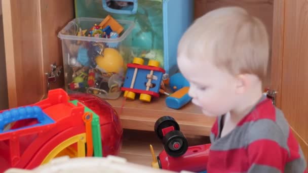 Маленький мальчик играет со своими игрушками — стоковое видео