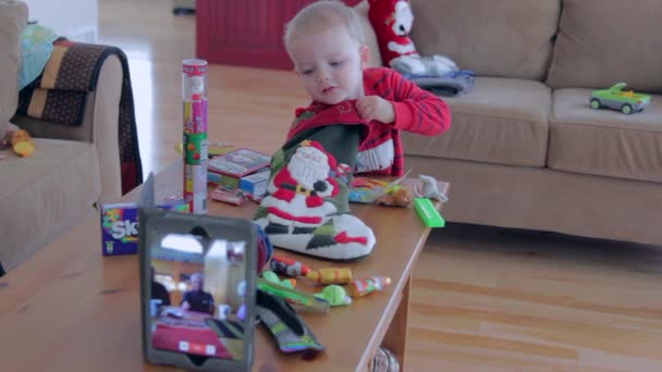 En liten pojke på juldagens morgon öppnar hans strumpa — Stockvideo