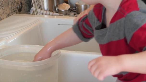 Toddler helps mother clean the dishes — Stock Video