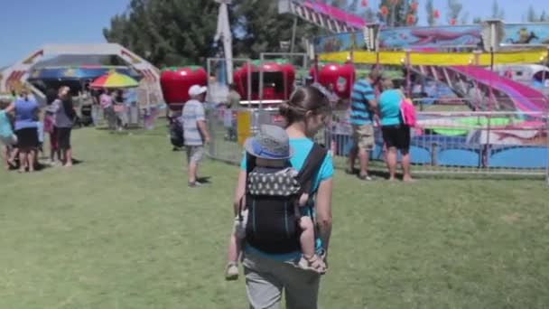 Une famille marchant à travers un carnaval — Video