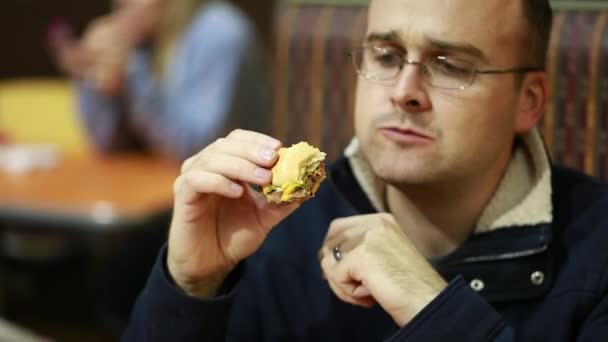 Un hombre comiendo hamburguesa — Vídeo de stock